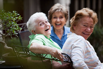 Three women laughing together outdoors in a garden