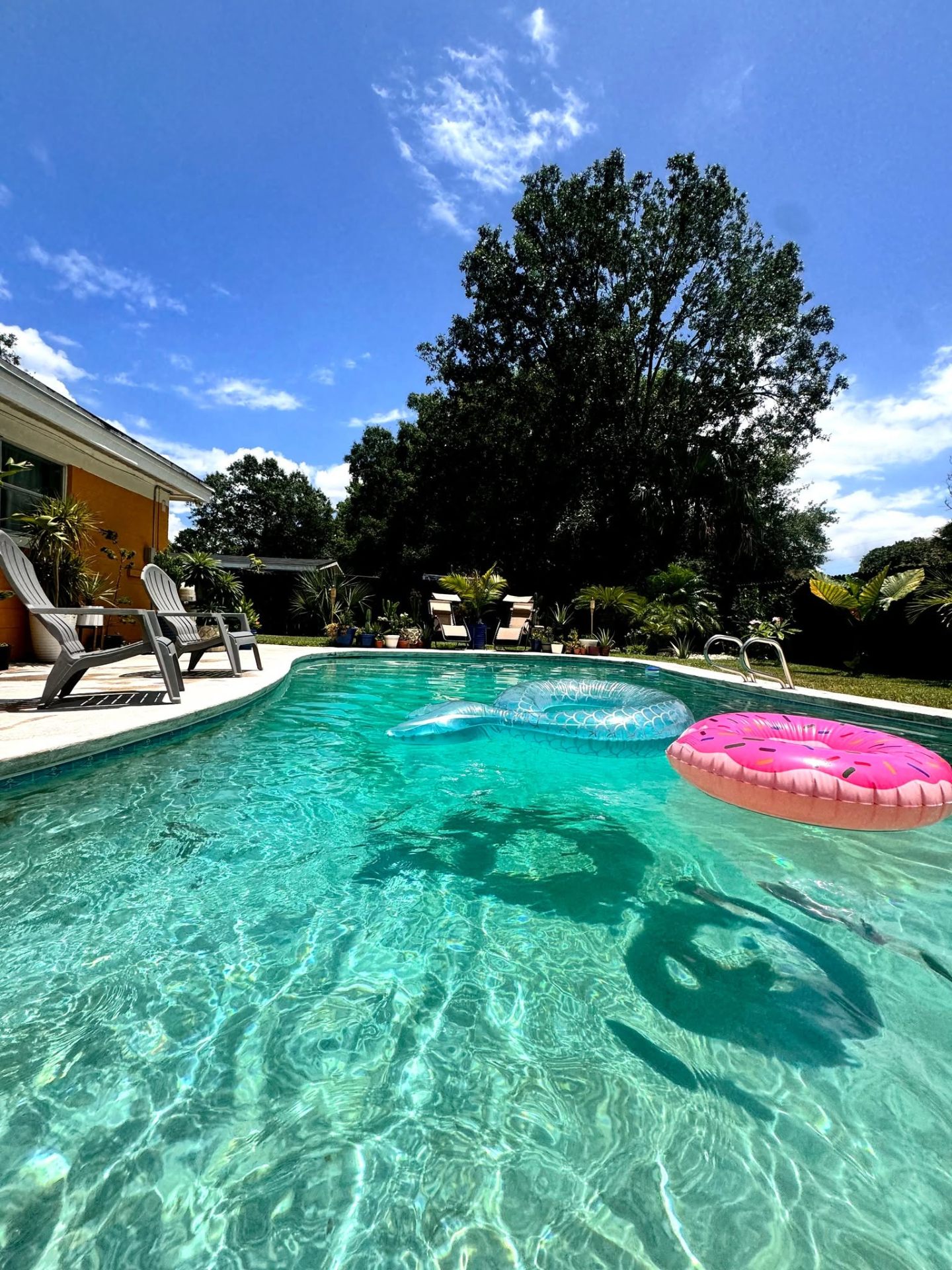 Crystal-clear pool with floats and lounge chairs under a Florida sky